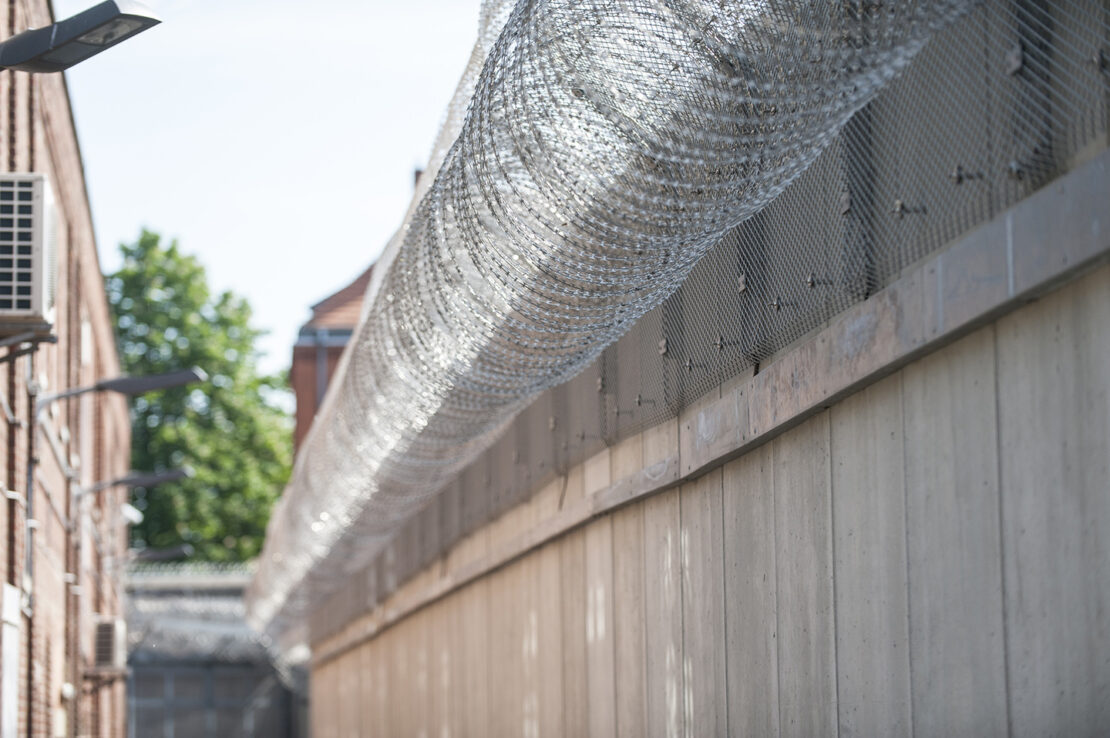 rote Gefängnisbacksteinmauer mit Stacheldraht